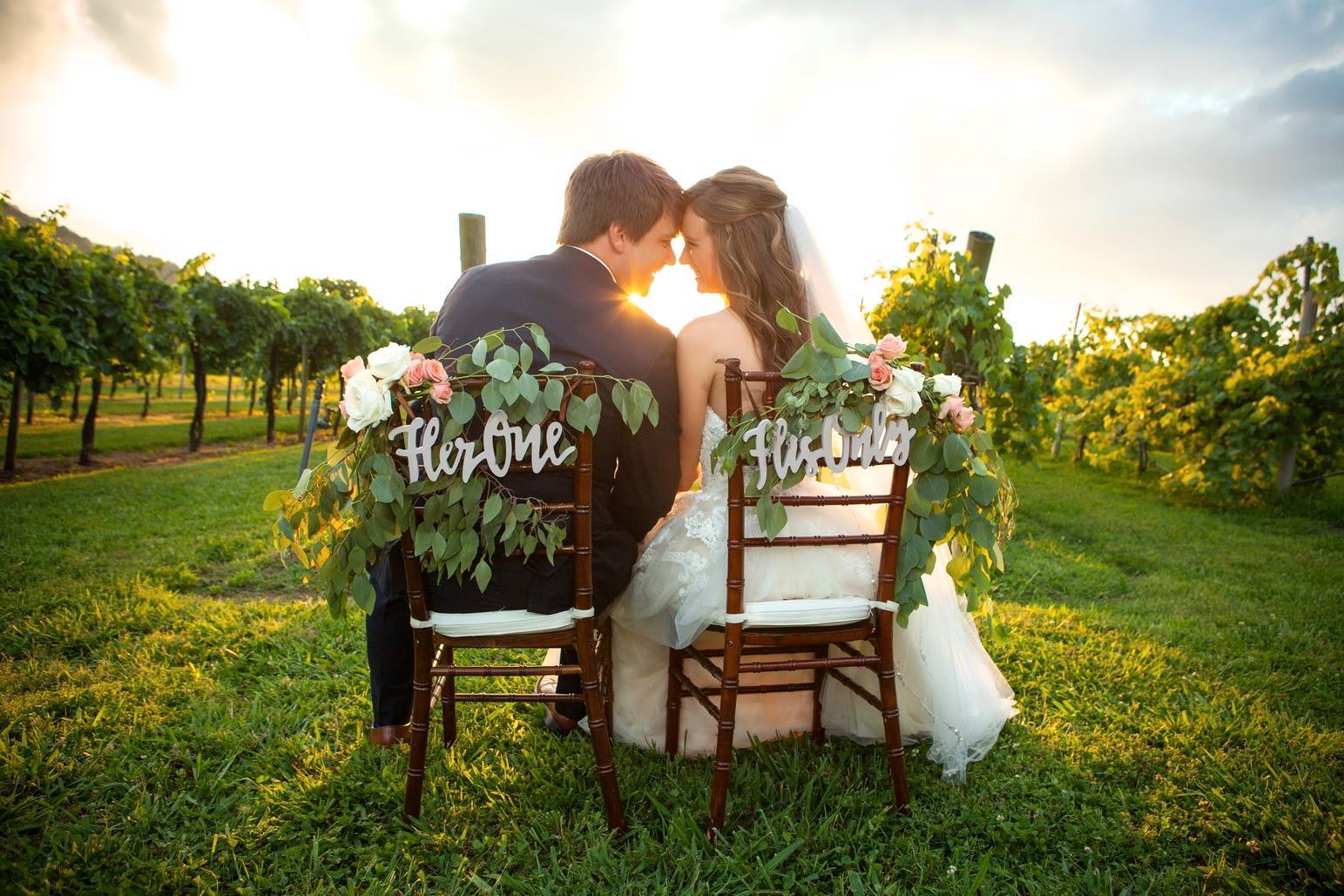 Bride and groom facing sunset on chairs adorned with signs and flowers from Designs by Melia by Barry Aslinger Photography | The Pink Bride® www.thepinkbride.com